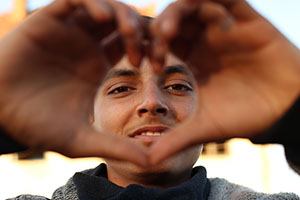 Young male refugee making a heart sign with his hands